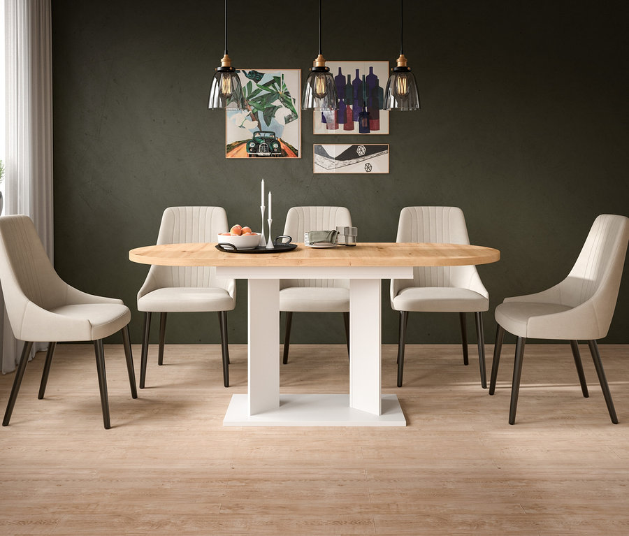 Ein Esszimmer mit einem ovalen Holztisch und sechs beigefarbenen Stühlen. Auf dem Tisch stehen eine Schale mit Orangen und Kerzen. Drei Hängelampen und drei Bilder schmücken die dunkelgrüne Wand.
