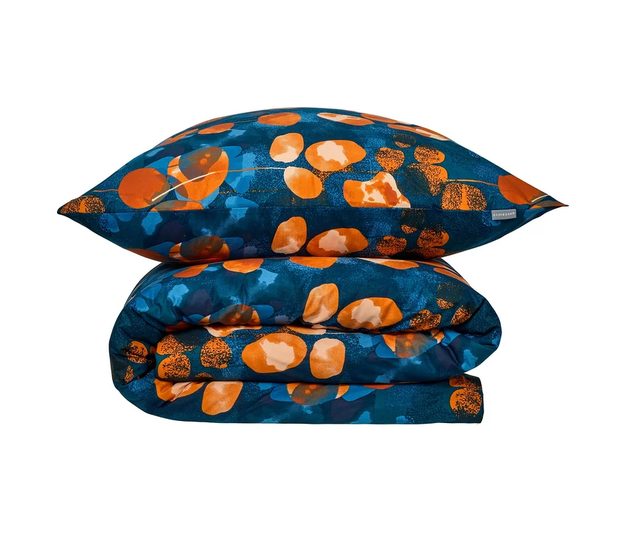 Kissen und gefaltete SCHIESSER Renforcé-Bettwäsche »Maxima« mit blauem Hintergrund und orange-blauen, abstrakten Formen.