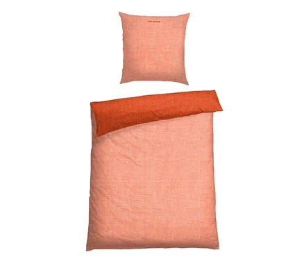 Bettwäsche-Set aus strukturiertem Stoff in Pfirsich- und Orangetönen, bestehend aus einem Kissenbezug mit "SCHIESSER" Aufschrift und einem Bettbezug mit umgeschlagenem orangefarbenen Rand.