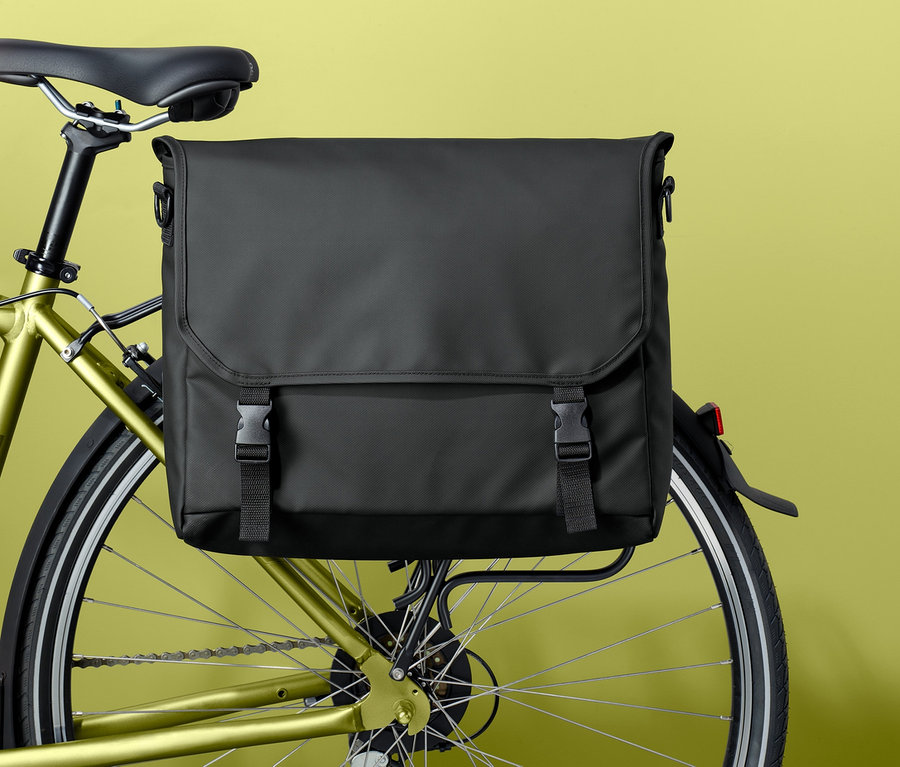 Eine schwarze Fahrrad- und Umhängetasche ist am Gepäckträger eines Fahrrads befestigt.