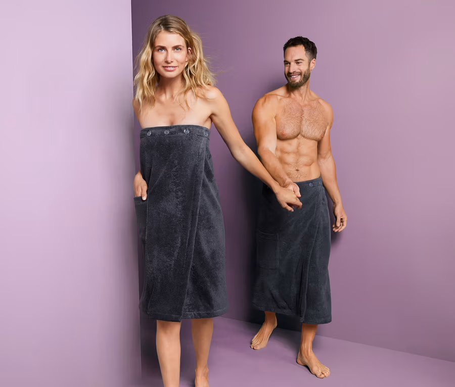 Eine Frau und ein Mann halten Händchen und tragen beide einen Unisex-Sauna-Kilt.