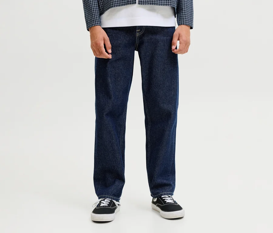 Eine Person trägt dunkelblaue Jack&Jones JJOriginal Chris Jeans, ein weißes T-Shirt, eine blau-weiß karierte Jacke und schwarze Sneaker.