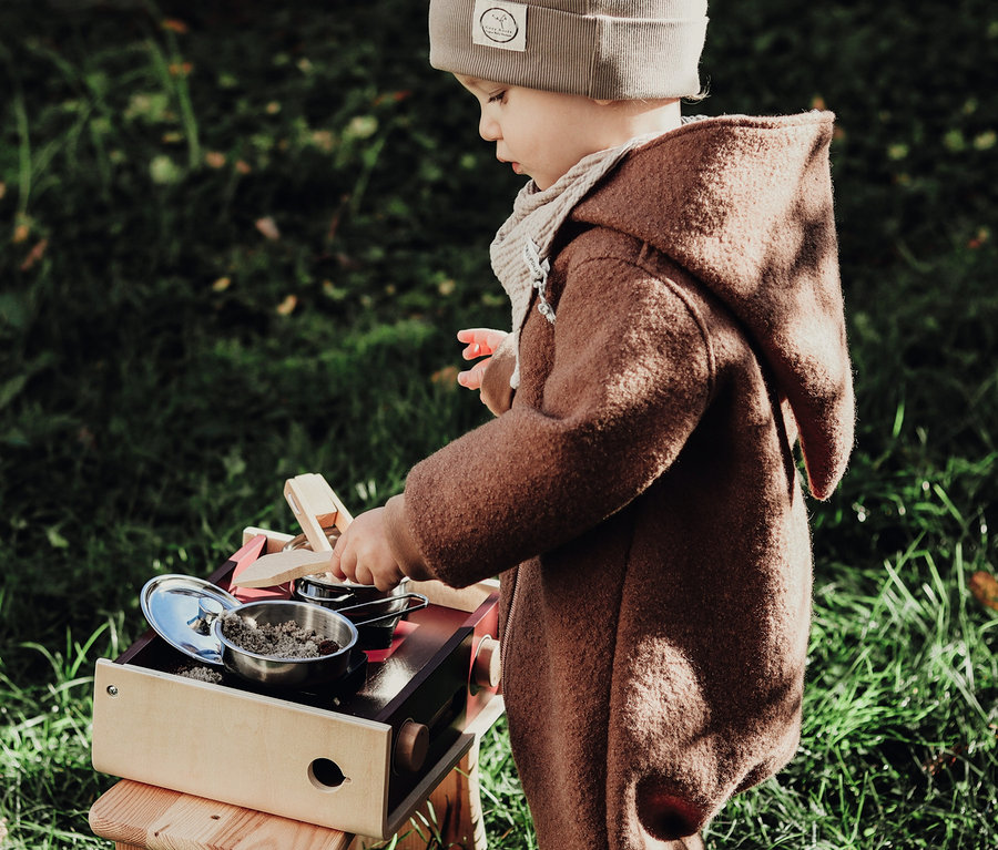Kind spielt mit small foot Kinderküche Camping »tasty« im Freien.