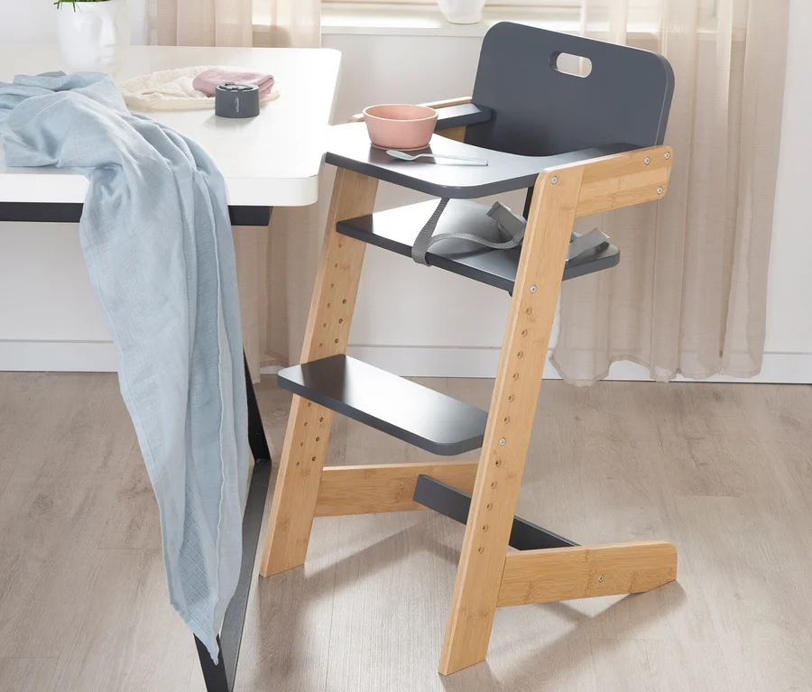 Ein anthrazitfarbener roba Babyhochstuhl steht neben einem Tisch.