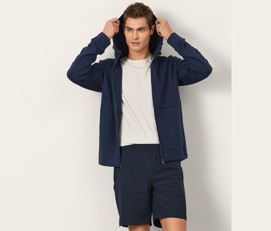 Mann zieht die Kapuze einer Funktionssweatjacke über den Kopf.