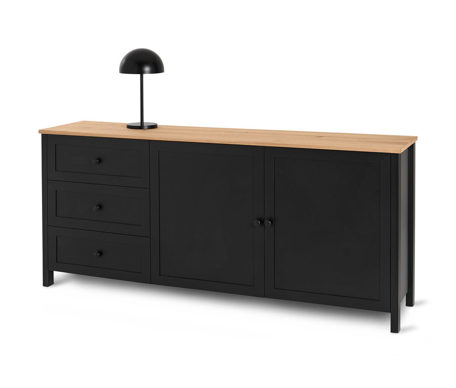 Schwarzes Sideboard »Clara« mit drei Schubladen und Türen steht unter einer schwarzen Lampe.