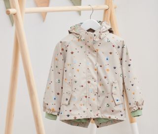 Eine Thermo-Regenjacke »Friesennerz« hängt an einem Holzständer mit Fähnchen und Spielzeug.