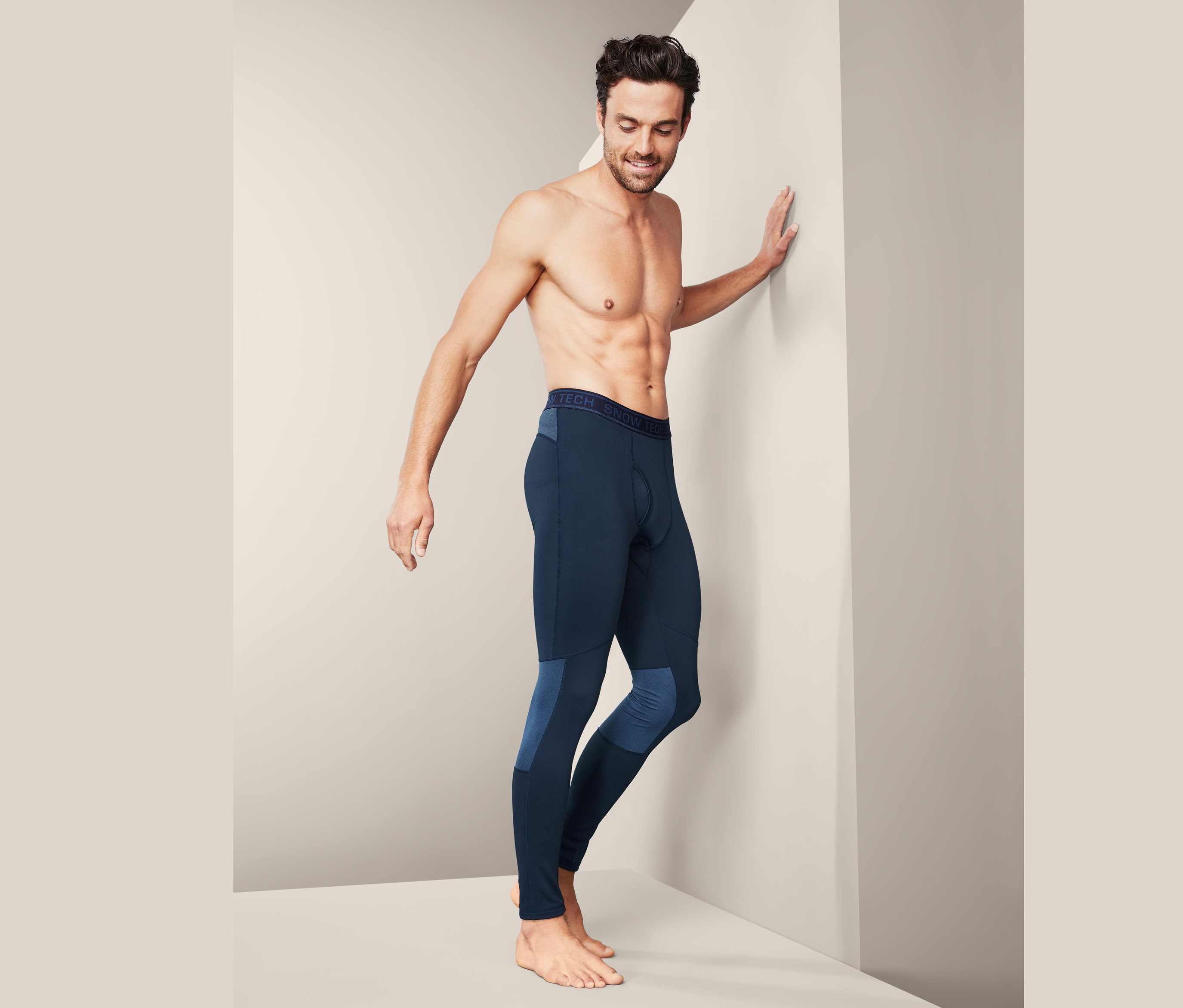 Mann lehnt an Wand, trägt Thermo-Funktionsunterhose.