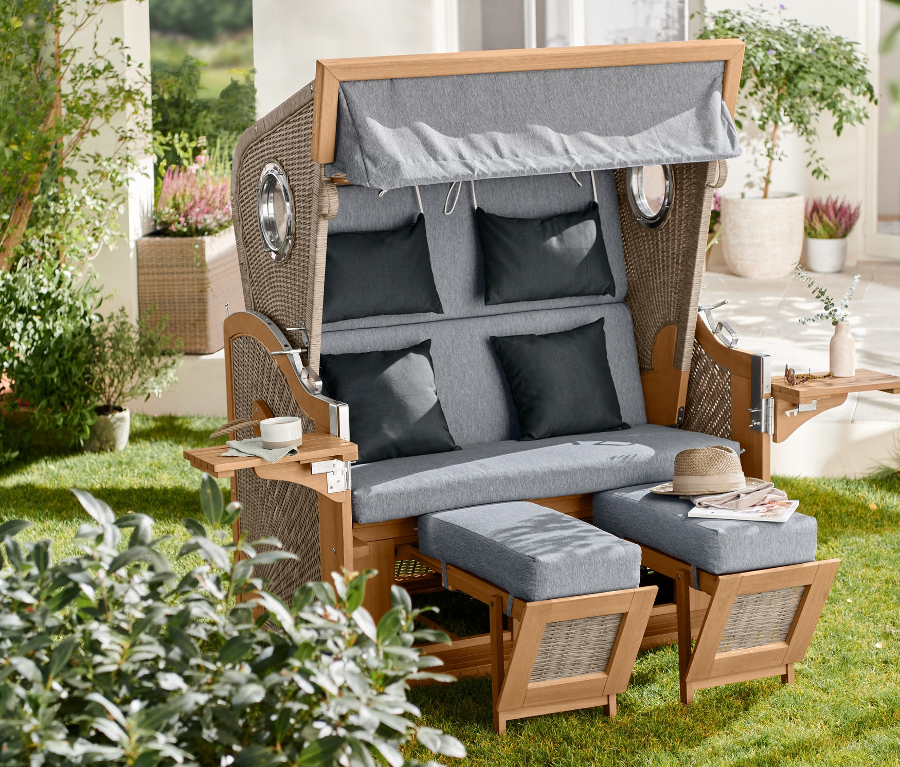 Premium-Strandkorb XXL mit 2 Schwenktischen steht auf einer Wiese.