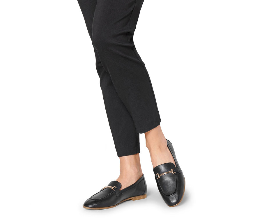 Beine in schwarzen Hosen und Leder-Loafern.