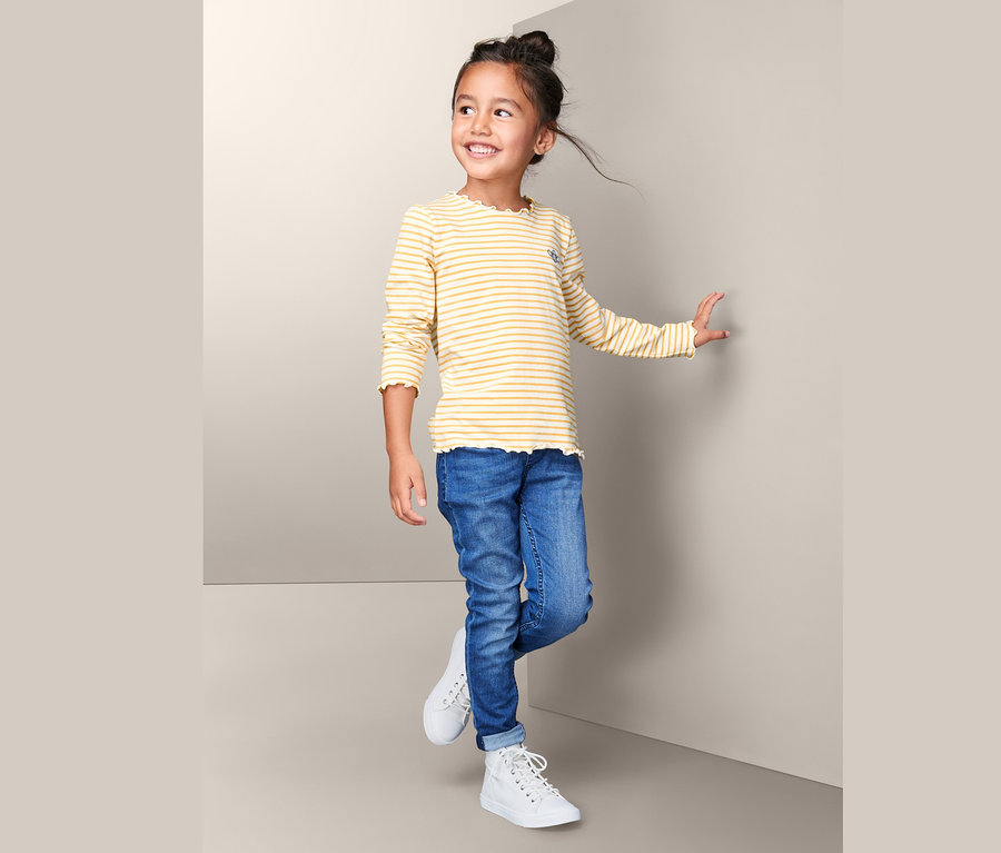 Mädchen trägt ein gelb-weiß gestreiftes Langarmshirt.
