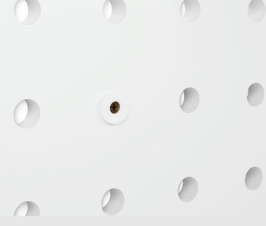 Detail eines weißen, flexiblen Wandregals mit Löchern und Schraube.