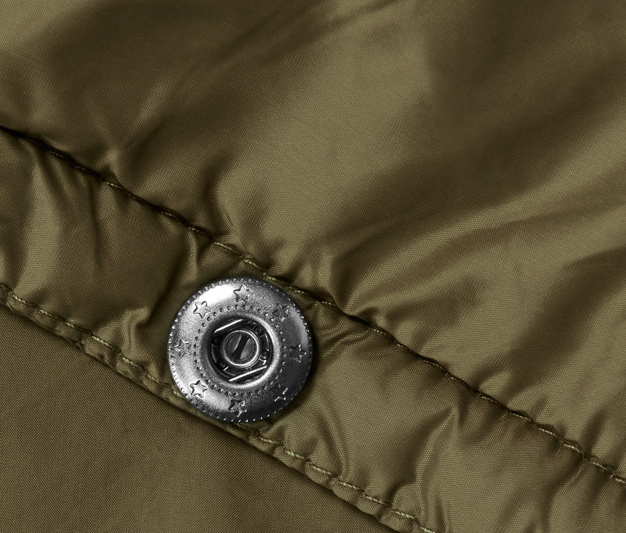 Detail einer ultraleichten Reisedecke mit silbernem Druckknopf.