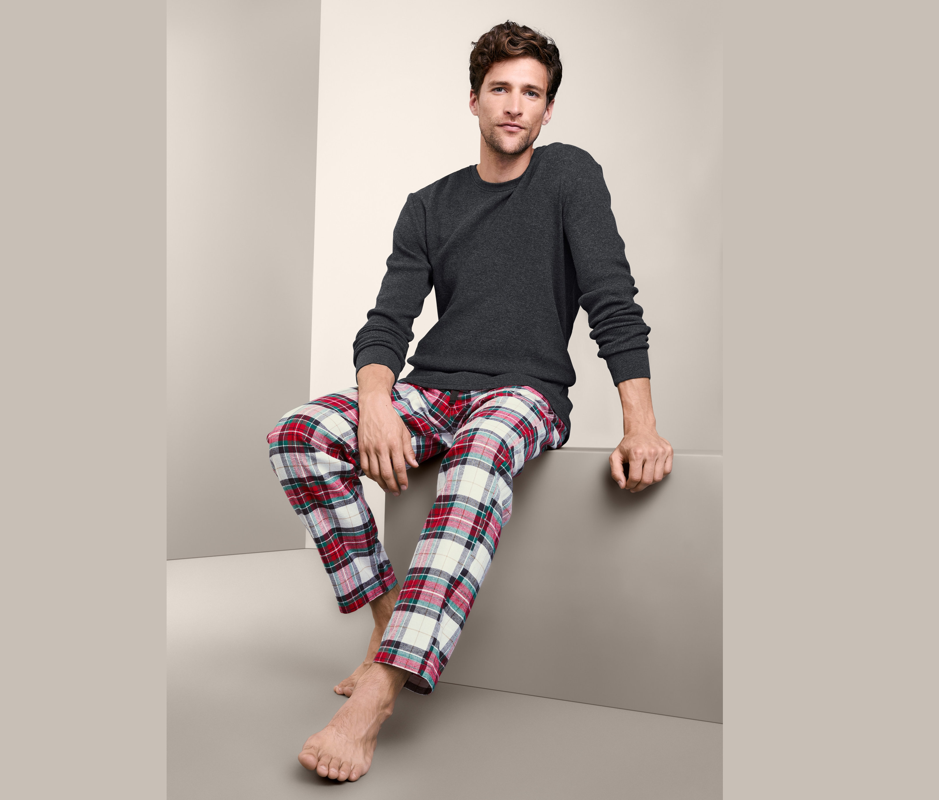 Mann sitzt und trägt einen Pyjama mit Flanellhose.