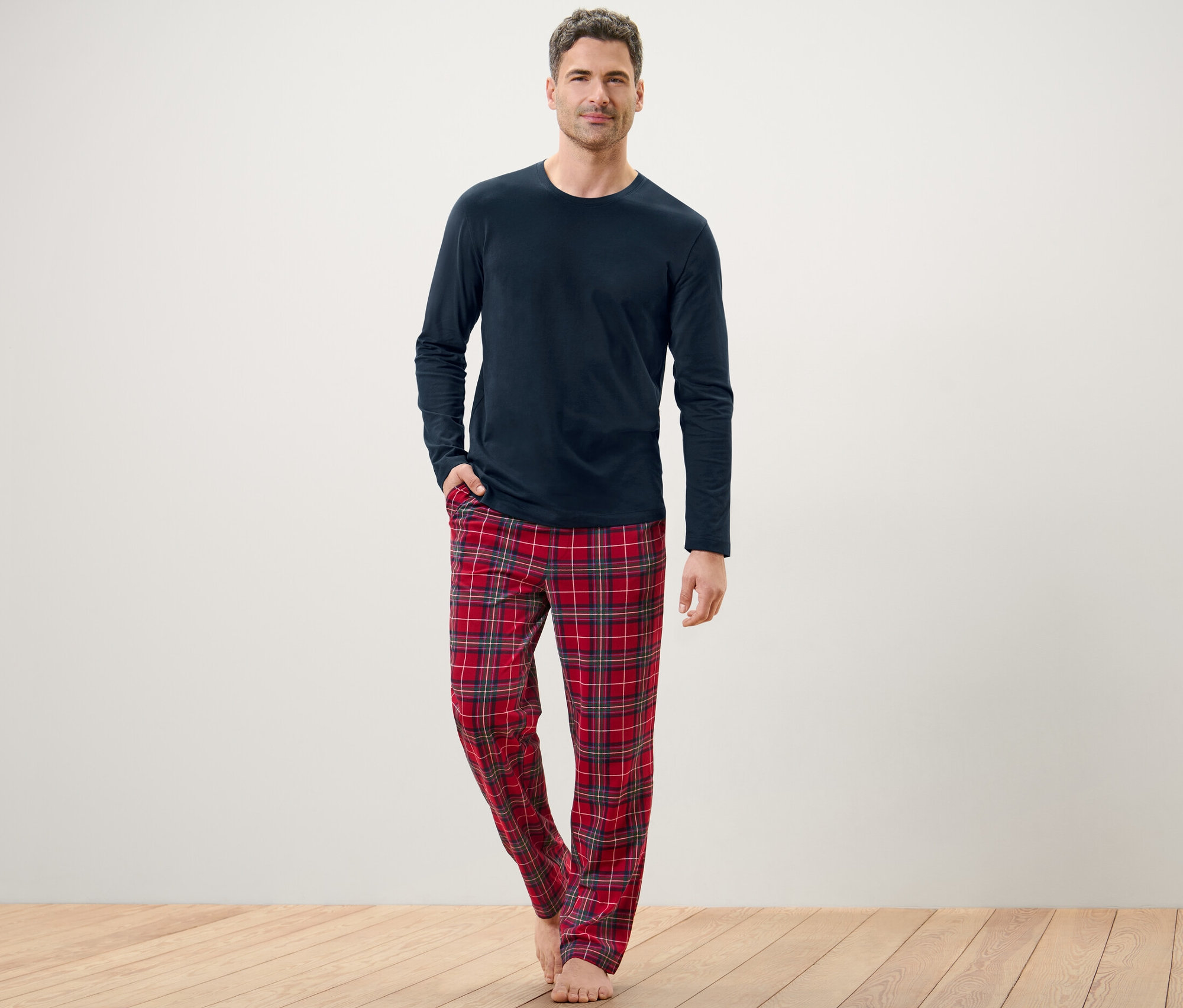 Mann posiert in blauem Pyjama mit karierter Hose.