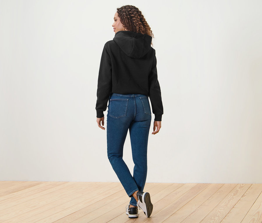 Frau von hinten in blauen Skinny Jeans – Fit »Hanna« und schwarzem Hoodie.