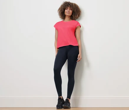 Frau steht und trägt eine Sporttight und ein T-Shirt.