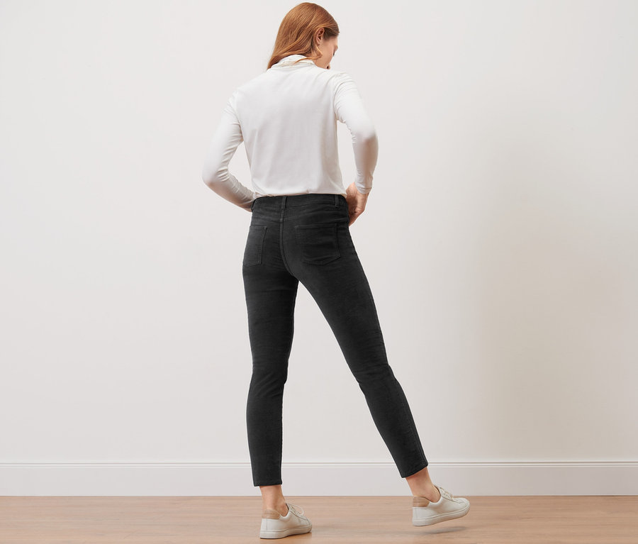 Eine Frau steht mit dem Rücken zur Kamera und trägt eine schwarze Samthose.