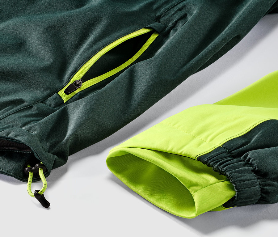 Detail einer Rad-Regenjacke in Grün mit neon-gelbem Reißverschluss.