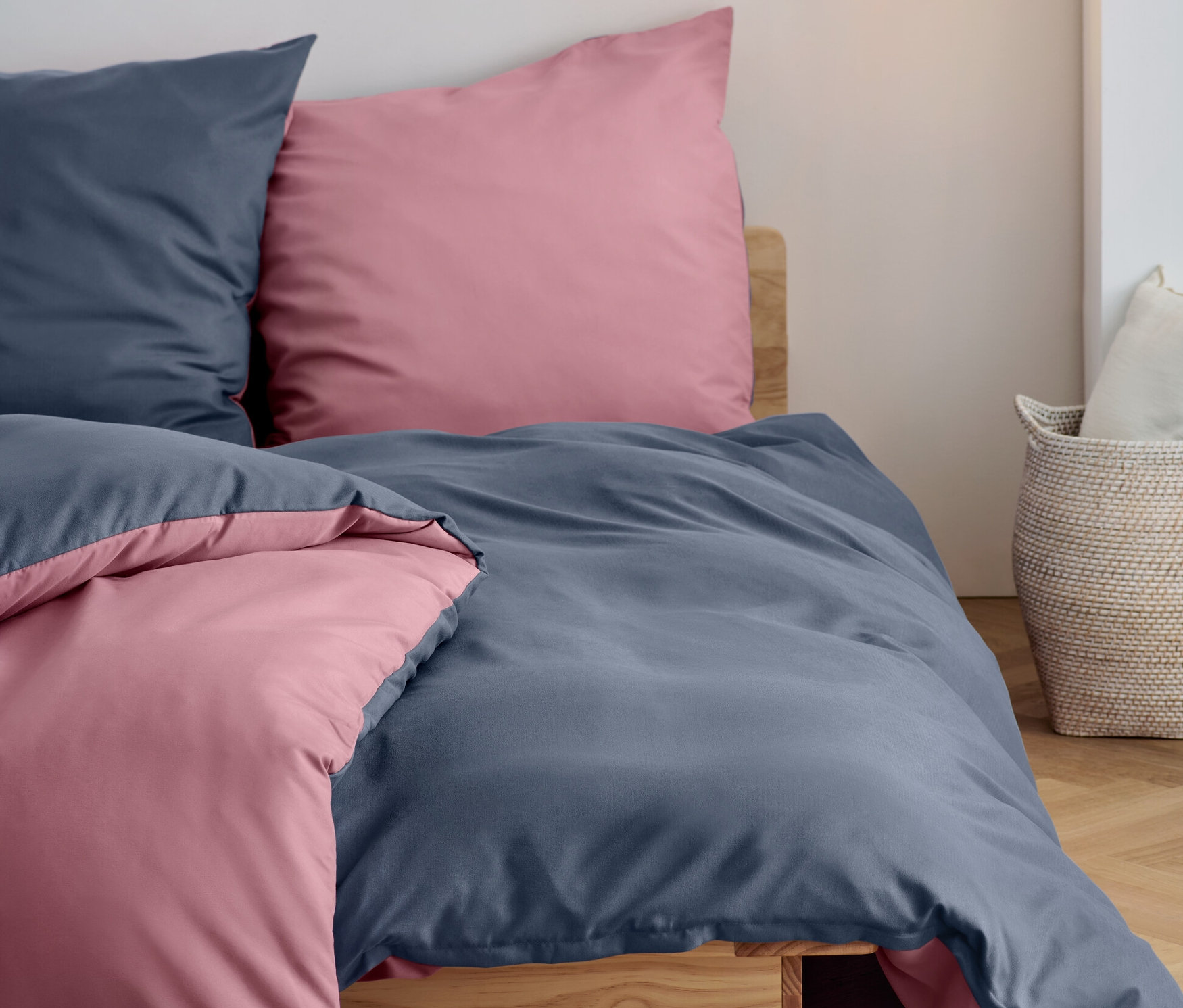 Zwei blaue und zwei rosa Kissen und Bettdecken aus Microfaser-Flanell-Bettwäsche in Normalgröße und Übergröße liegen auf einem Bett.