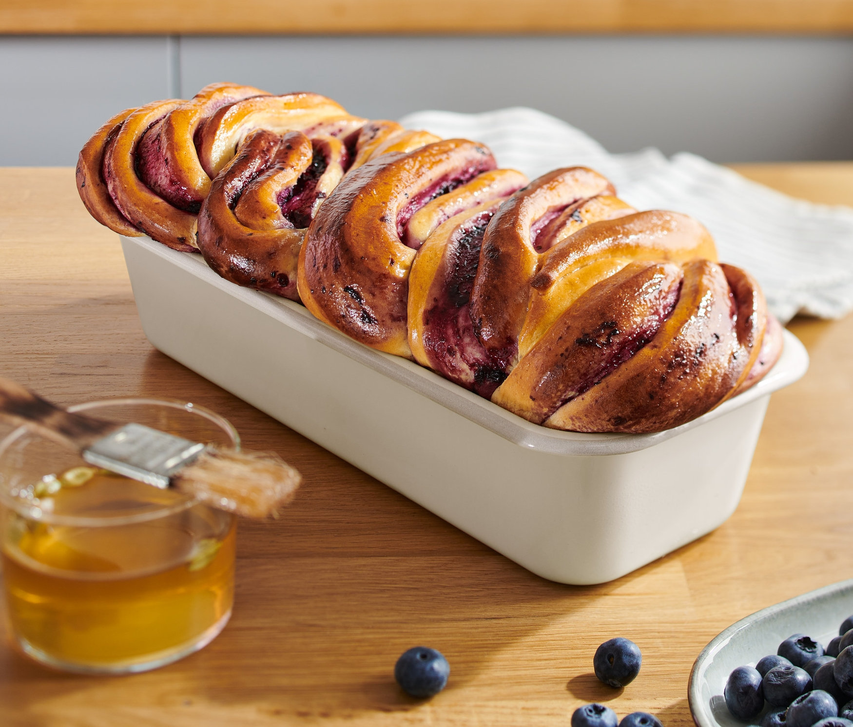 Ein gebackener Kuchen in einer Emaille-Kastenform mit Blaubeeren.