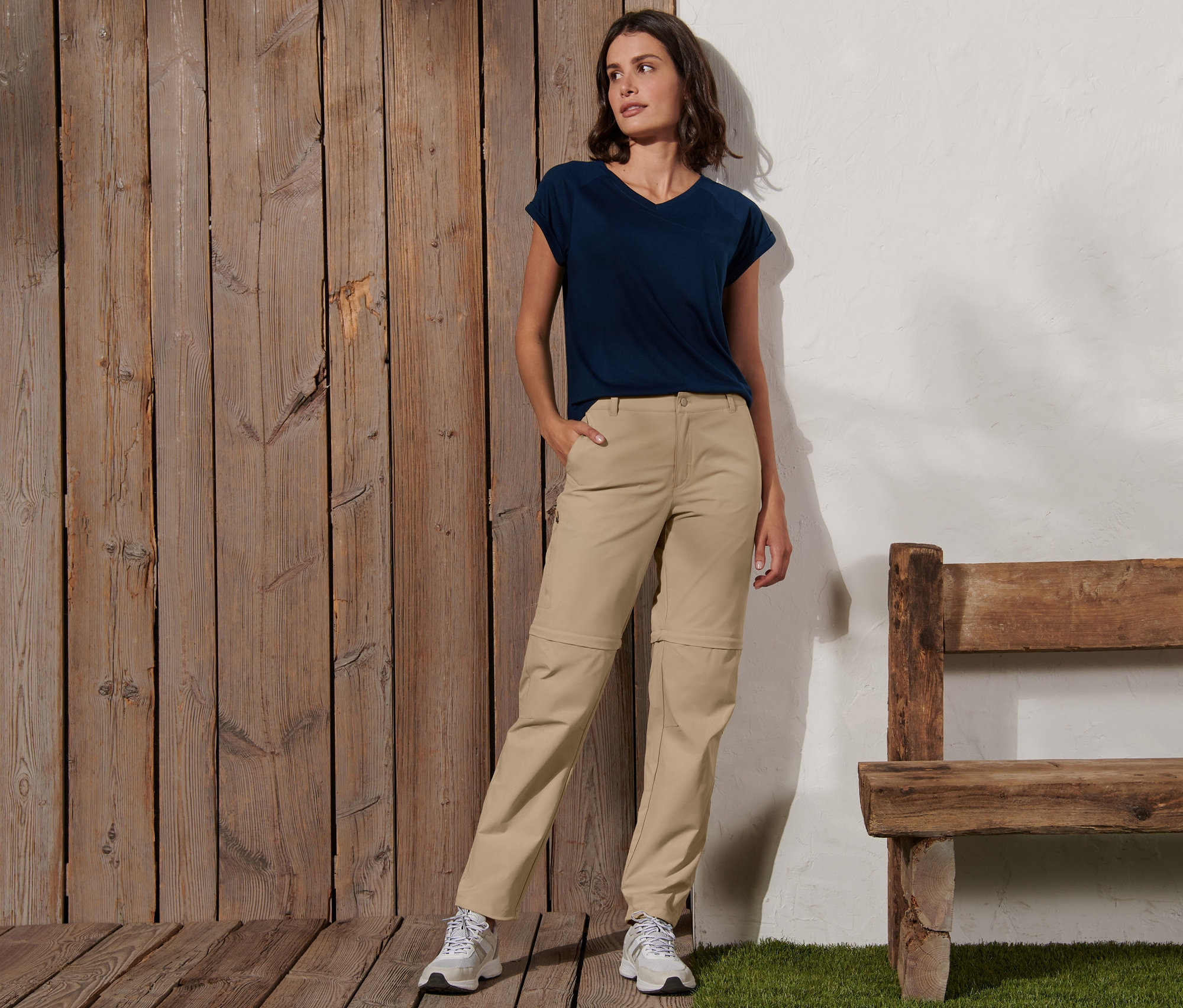 Frau posiert in einer 2-in-1-Funktionshose in Creme und einem blauen T-Shirt.