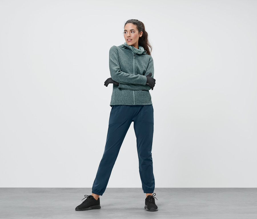 Frau trägt eine mintfarben melierte Strickfleece-Jacke, eine Thermojacke in Mint und eine Thermohose.