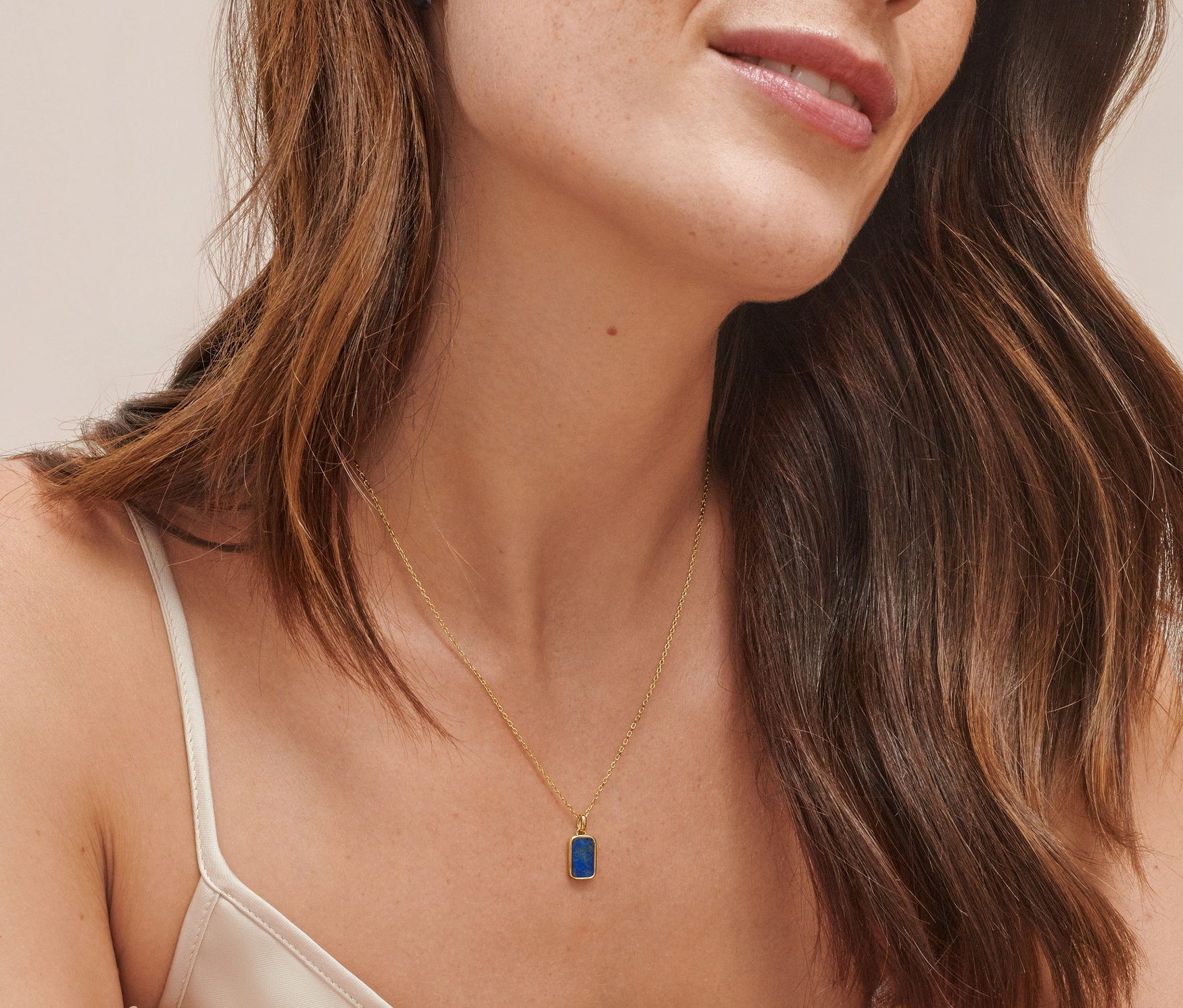 Eine Frau trägt Creolen aus zweifarbigem 925er Silber und eine Kette aus vergoldetem 925er Silber mit Lapislazuli.