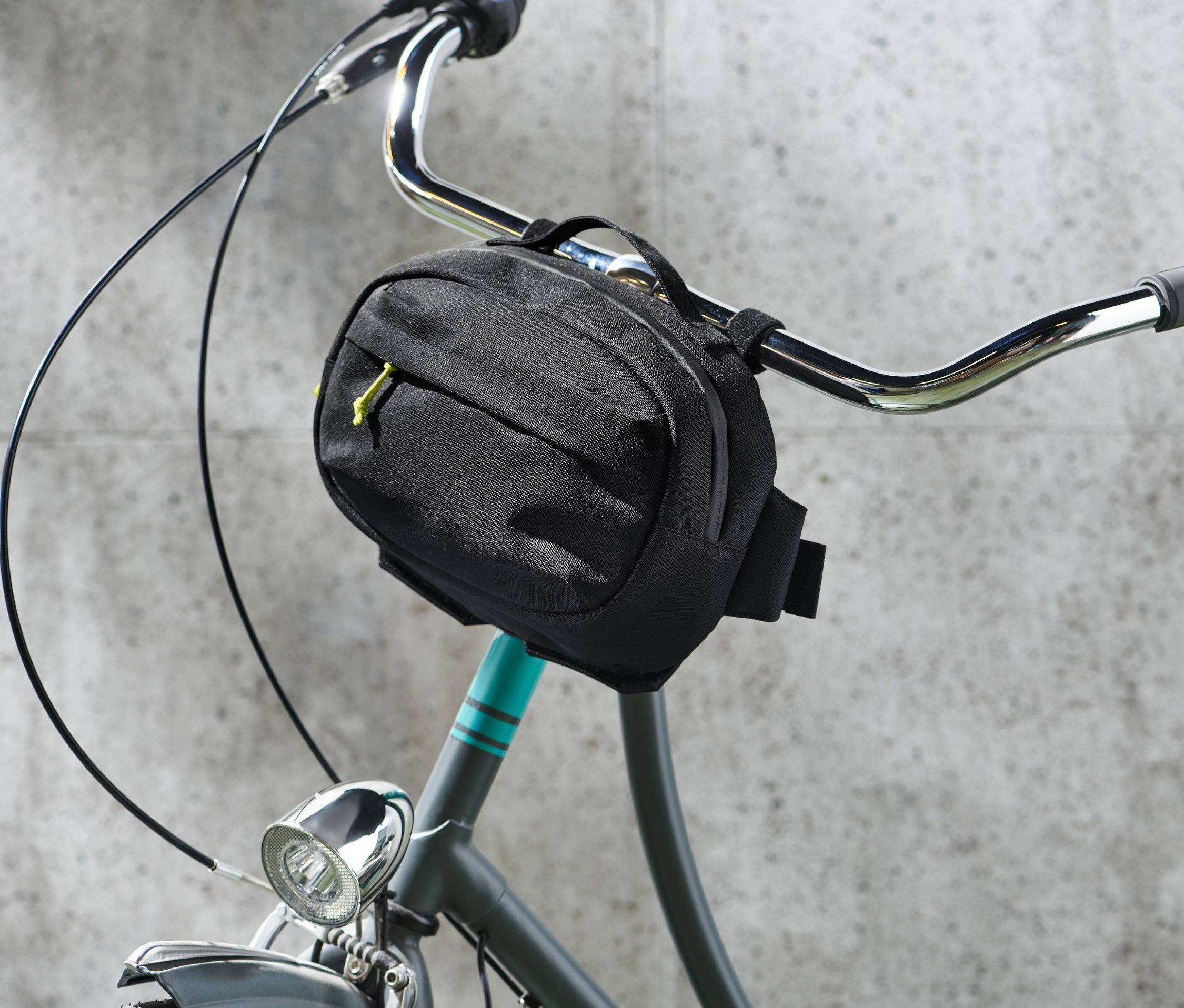 Eine schwarze 2-in-1-Lenkertasche ist an einem Fahrradlenker befestigt.