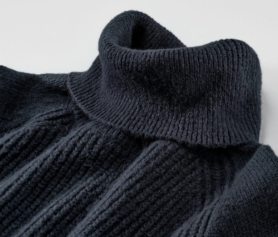 Detailansicht eines dunkelblauen Grobstrickpullovers mit Rollkragen.