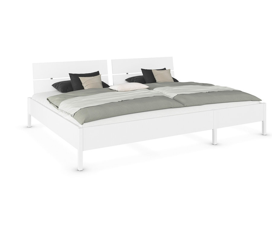 Weißes Doppelbett mit zwei Liegeflächen, Kissen und grauem Überwurf.