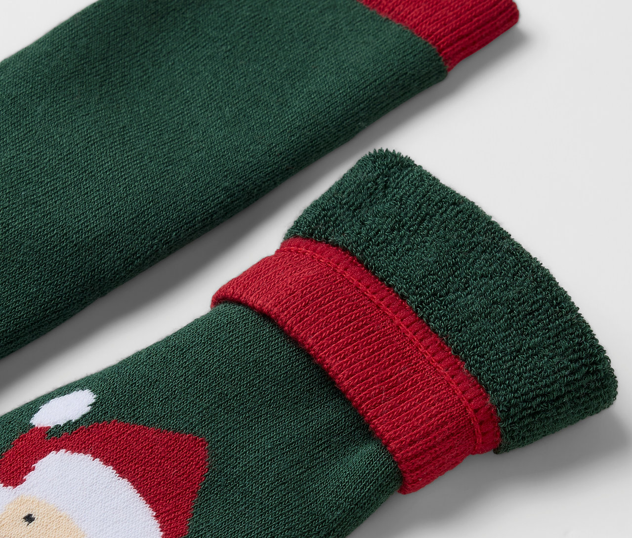Detailaufnahme einer grünen Socke mit rotem Rand und Weihnachtsmann-Motiv.