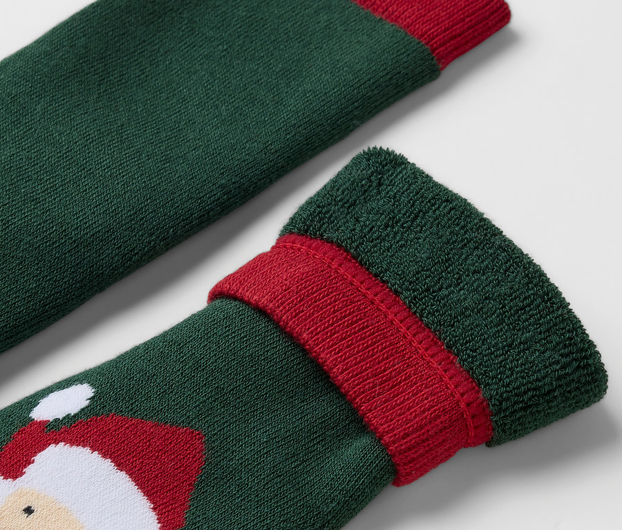 Detailaufnahme einer grünen Socke mit rotem Rand und Weihnachtsmann-Motiv.
