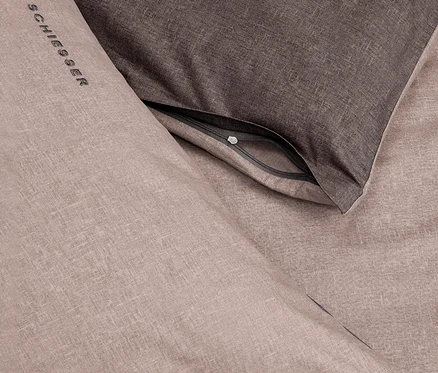 SCHIESSER Renforcé-Kissenhülle in Taupe und Dunkelgrau, mit sichtbarem Reißverschluss und Logo.