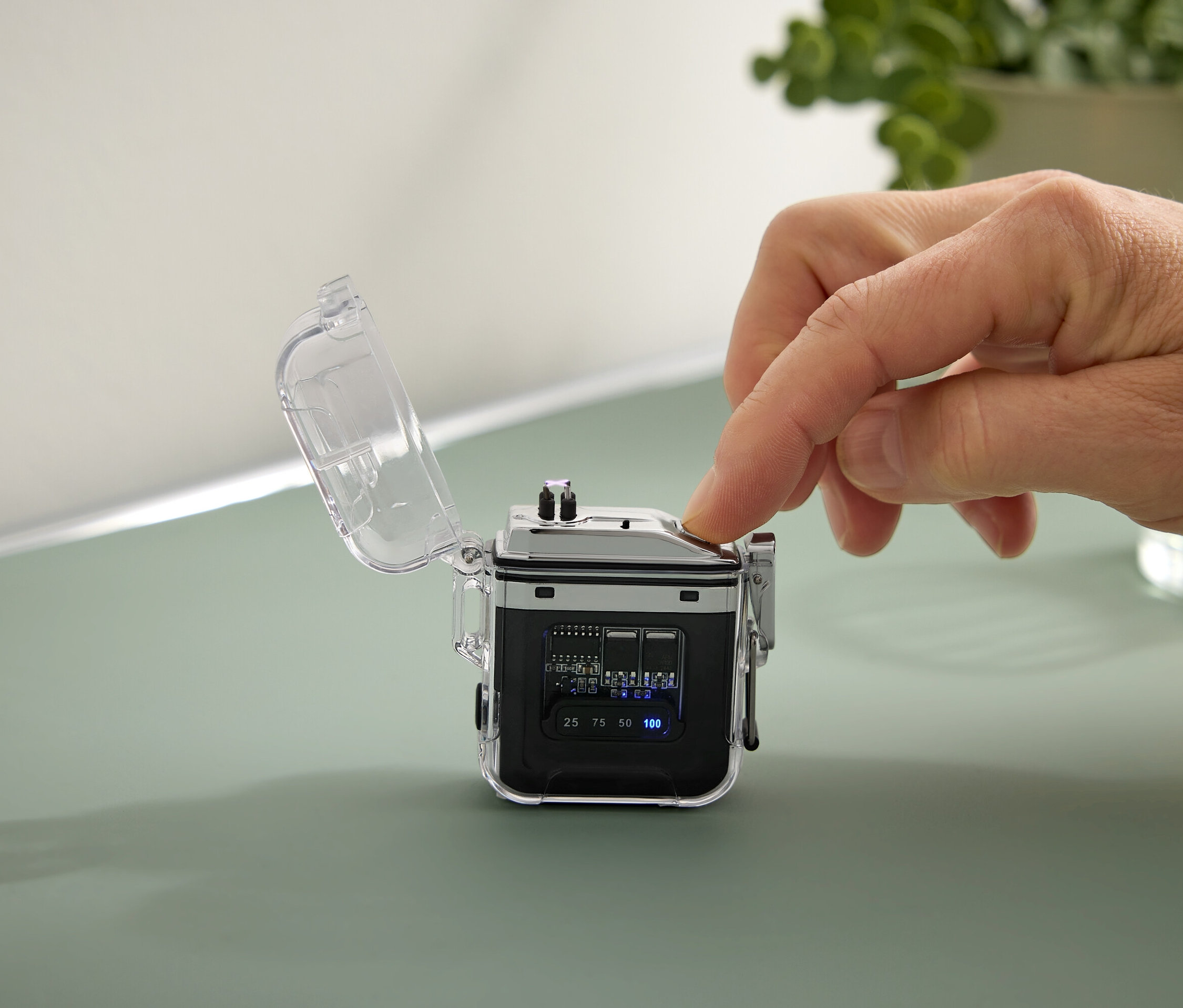 Eine Hand drückt einen Knopf an einem kleinen, schwarzen Gerät mit einem transparenten Gehäuse.