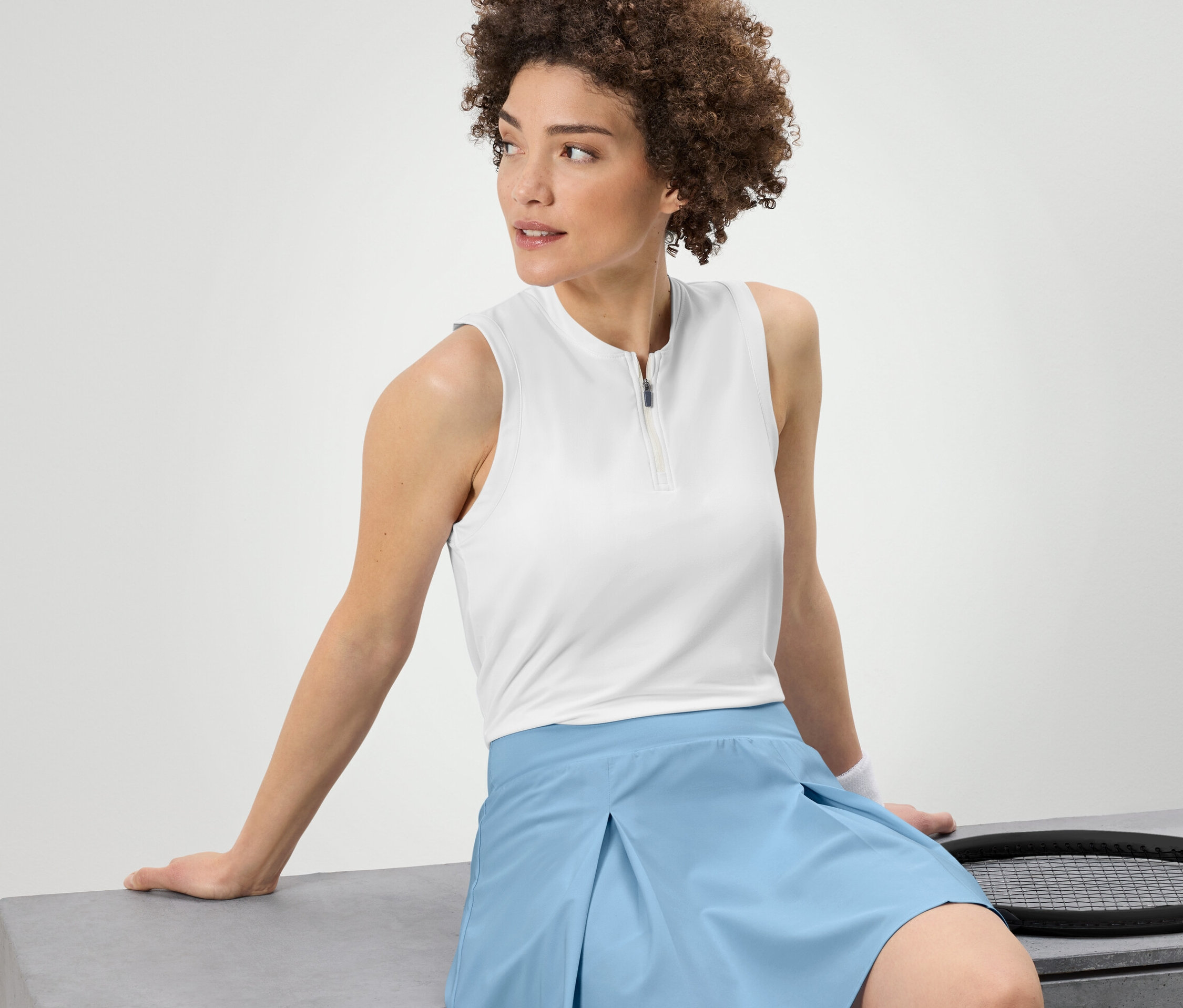 Frau sitzt und trägt ein weißes Funktionstop.