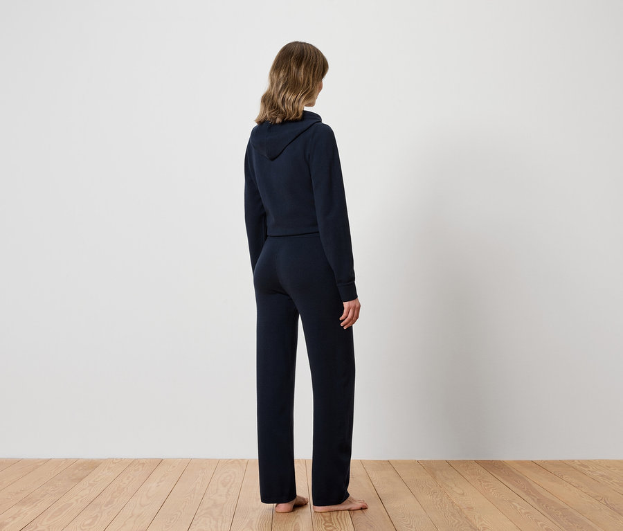 Frau mit dem Rücken zur Kamera trägt einen marineblauen Hoodie und eine Trainingshose.