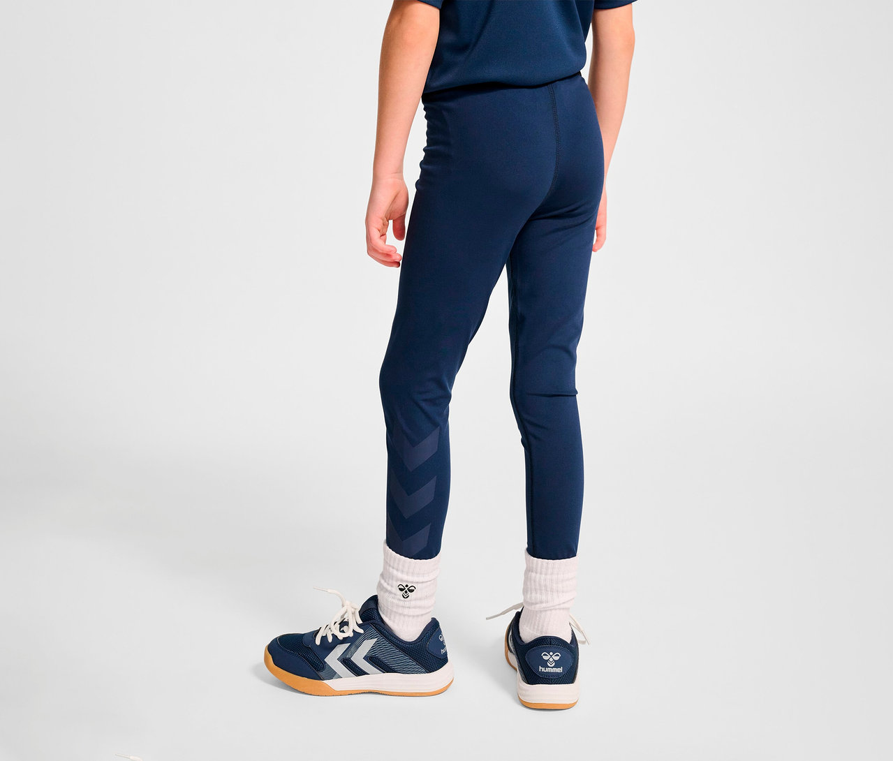 Junge von hinten trägt blaue HUMMEL HMLJR Pulse Mid Waist Tight und Turnschuhe.