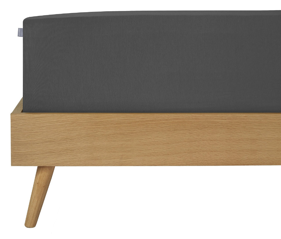 Dunkelgraues SCHIESSER Edeljersey-Spannbettlaken »Jessi« auf einem Holzbettrahmen.