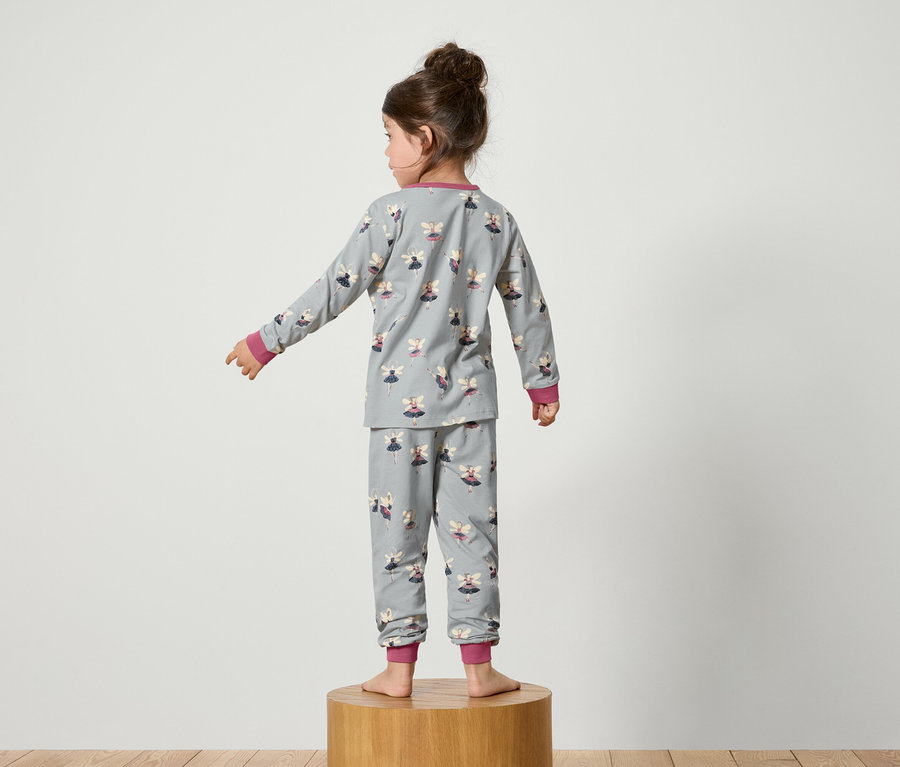 Mädchen steht mit dem Rücken zum Betrachter und trägt einen grauen Schlafanzug mit Feenmuster.