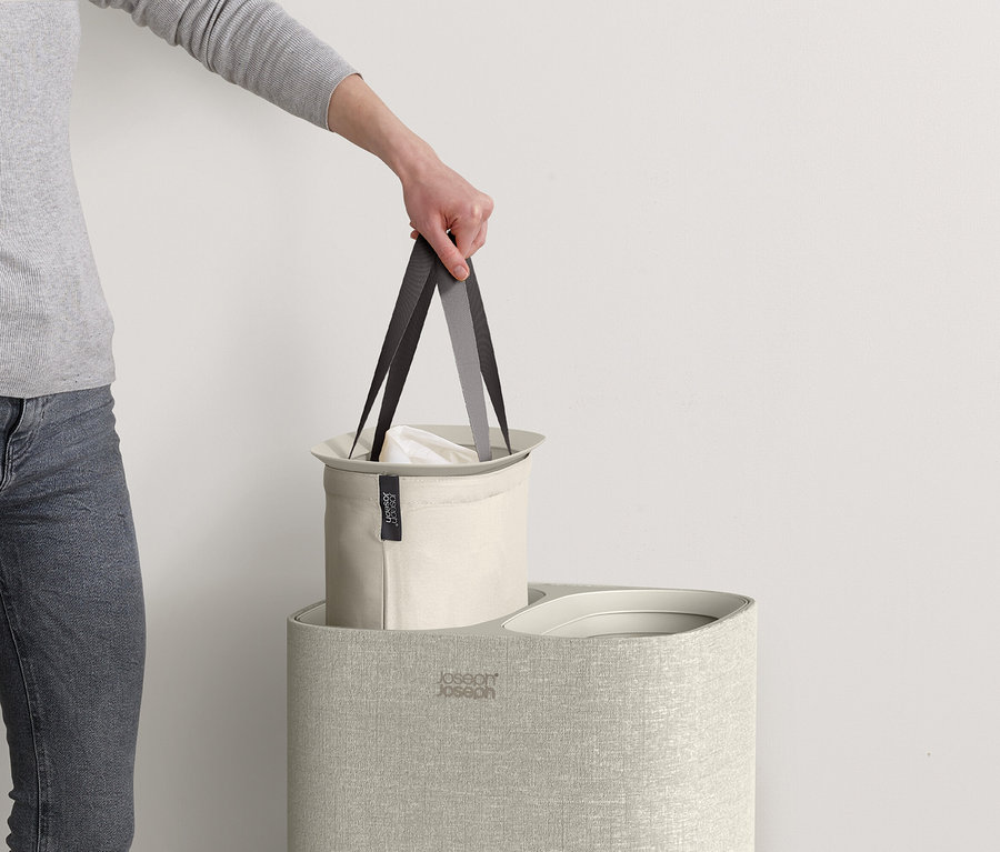 Eine Hand hält einen Joseph Joseph Sort Bin Wäschekorb hoch.