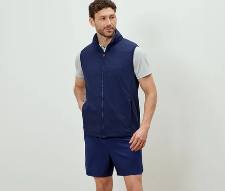 Mann trägt eine marineblaue Funktionsweste »packable« und Shorts.