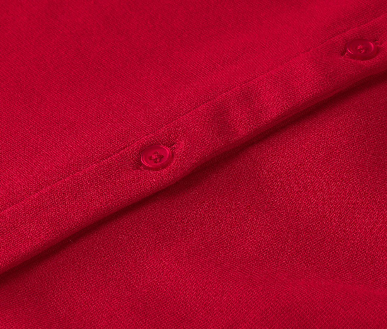 Detailaufnahme eines roten Kleidungsstücks mit Knöpfen.