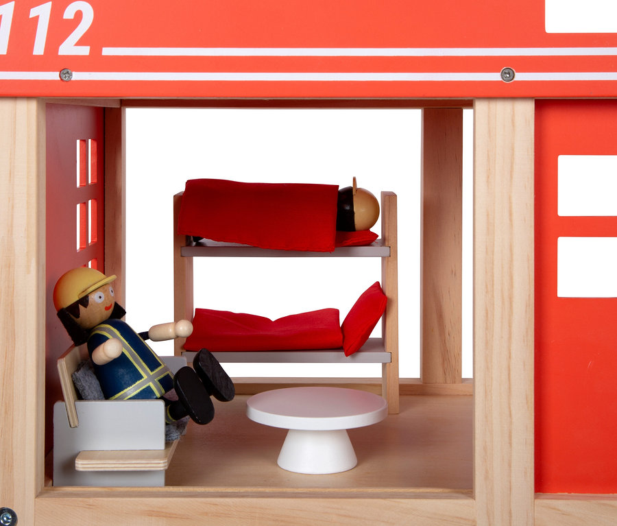 Eine Feuerwehrmann-Figur sitzt in einem Sessel in einer Feuerwache mit einem Etagenbett und einem runden Tisch.