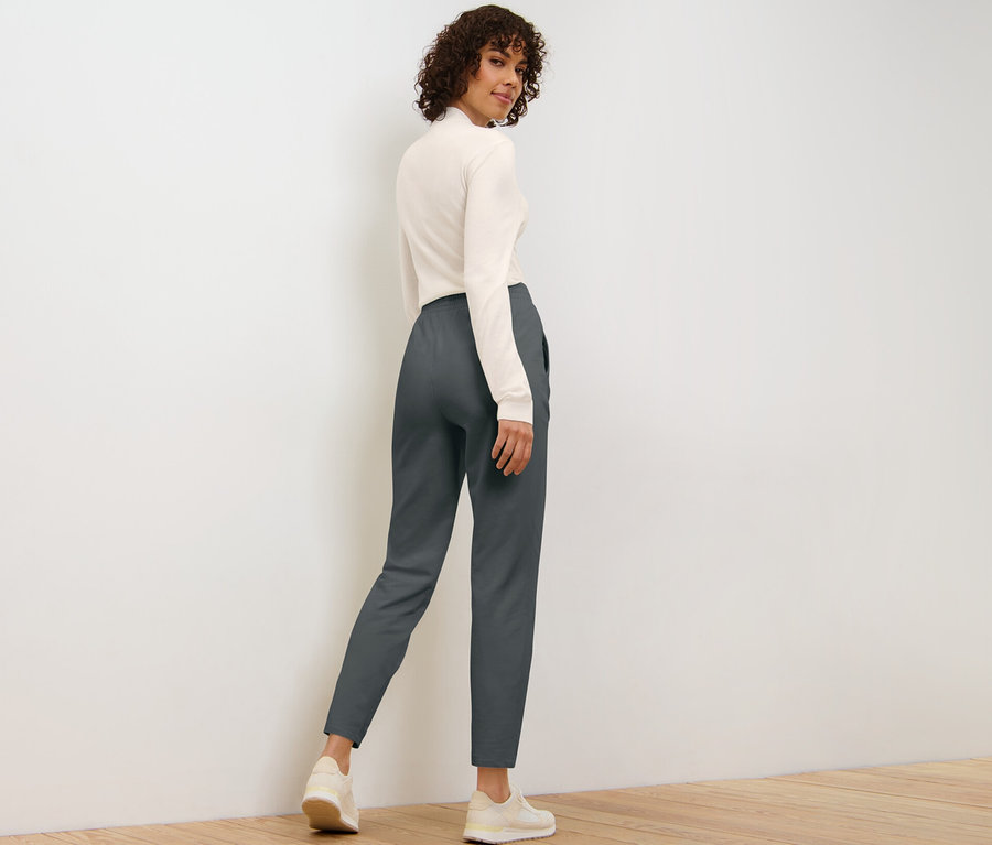 Frau blickt über die Schulter und posiert in Joggpants.