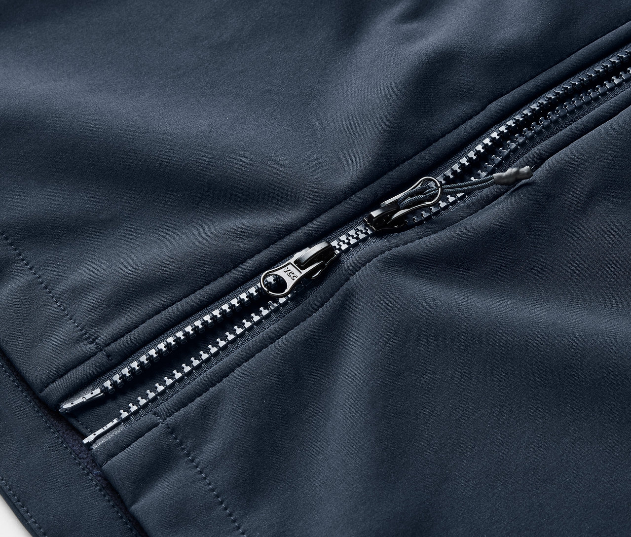 Detailansicht eines marineblauen Softshellmantels mit silbernem Reißverschluss.