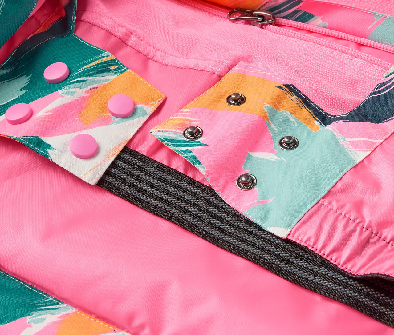 Detail einer Jacke mit rosa Futter, bunten Mustern und Druckknöpfen.