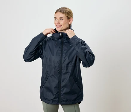 Frau, die eine marineblaue Jacke mit Kapuze anpasst und lächelt.