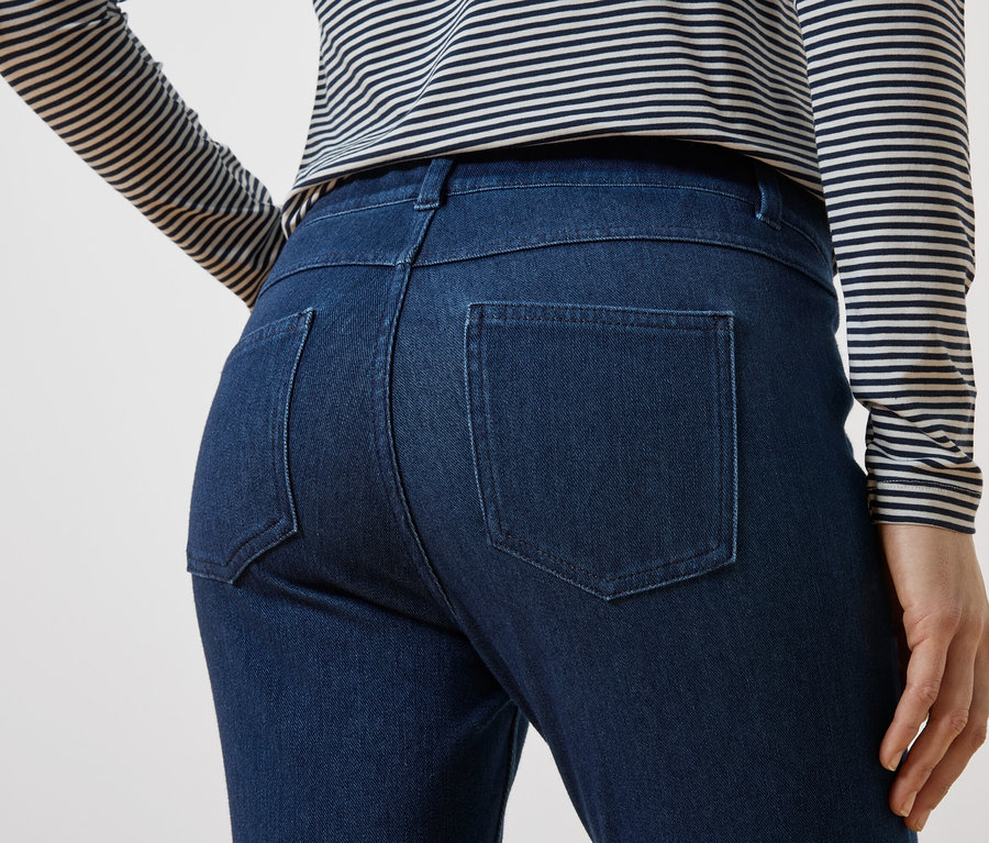 Rückansicht einer Person in dunkelblauen Jeans und einem gestreiften Oberteil.
