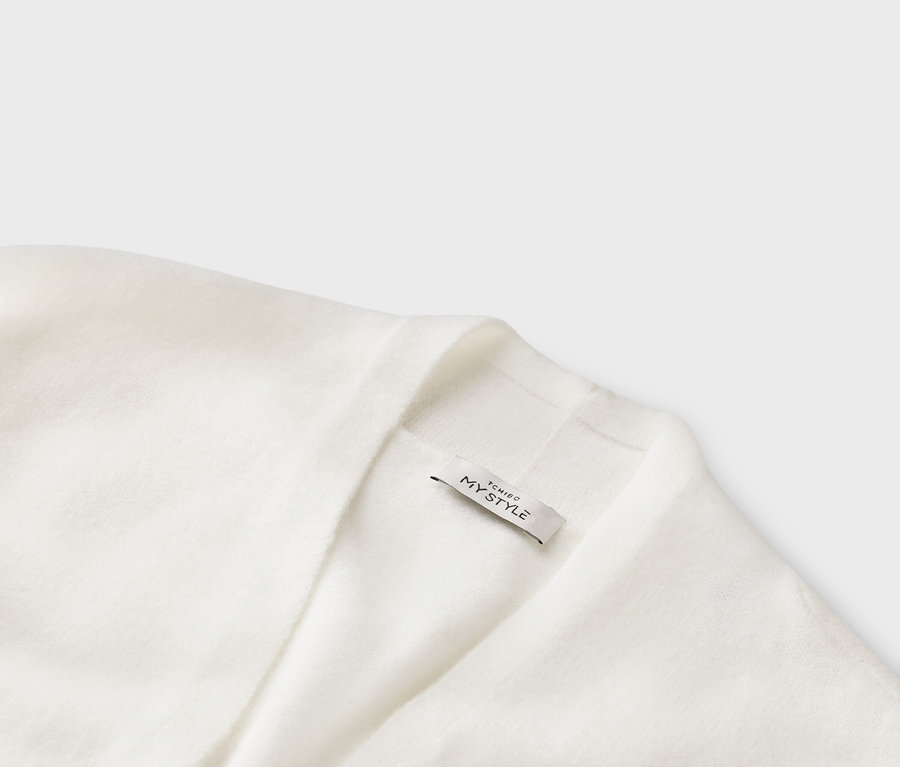 Nahaufnahme einer weißen Strickjacke mit einem Etikett mit der Aufschrift "TCHIBO MY STYLE".